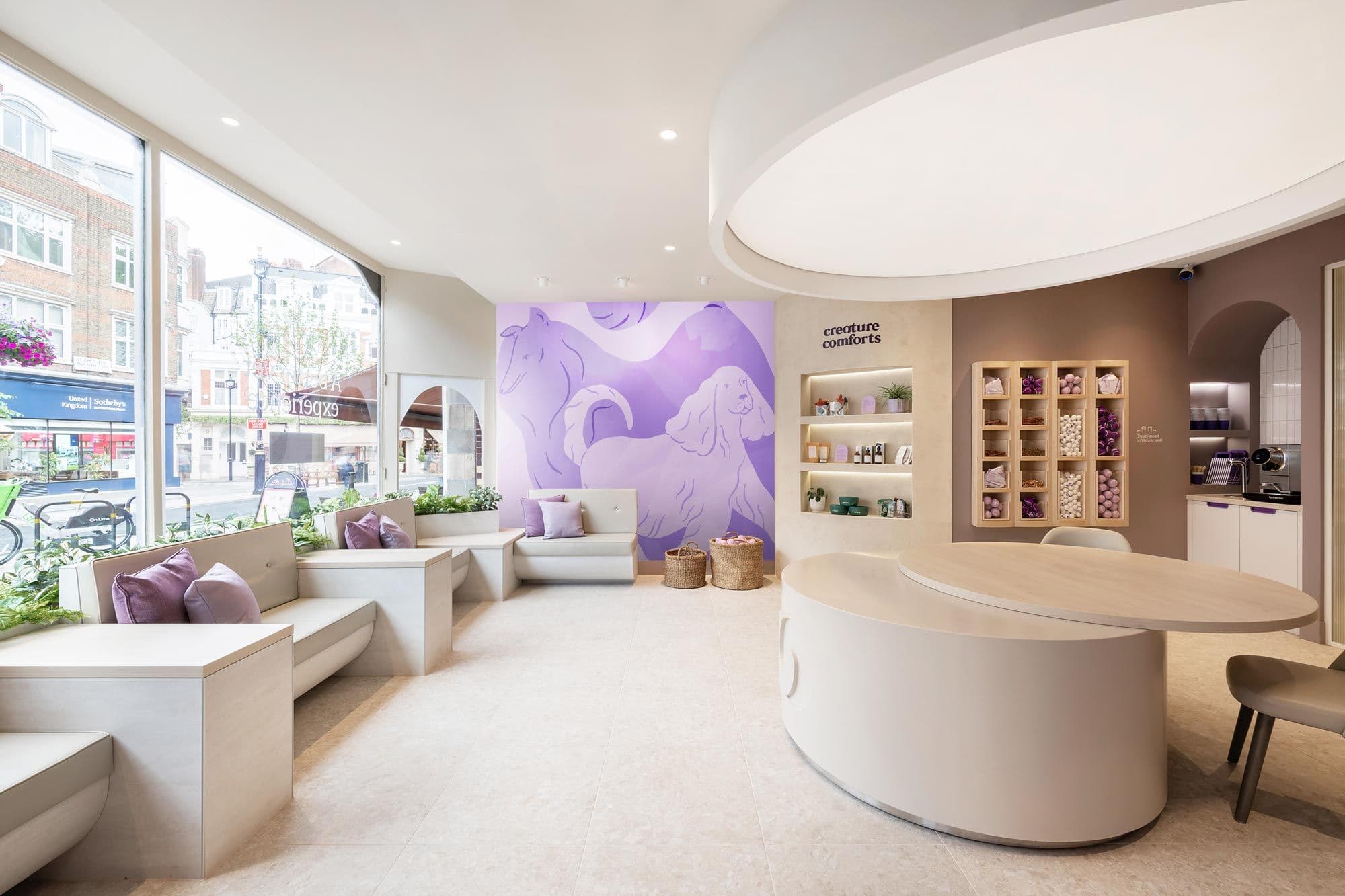 A bright interior view of Creature Comfort's St Johns Wood clinic with welcoming sofas, pet toys and Creature Comforts branding on the wall. 